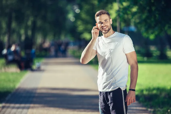 밖에 서 운동 하는 동안 음악을 듣고 웃는 남자 — 스톡 사진