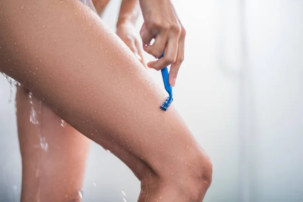 Woman hand shaving thigh in shower — Stockfoto