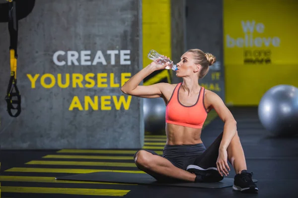 Atlética dama está bebiendo agua en el gimnasio —  Fotos de Stock