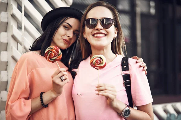 Оптимистичные женщины едят конфеты на улице — стоковое фото