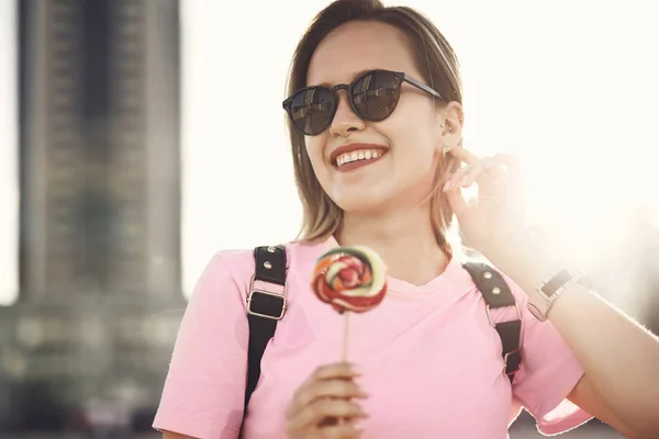 Chica satisfecha degustación piruletas en la calle —  Fotos de Stock