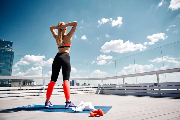 Slim signora si sta riscaldando-up prima di fitness sul tetto soleggiato — Foto Stock
