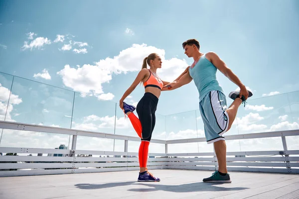 El hombre y la mujer se apoyan mutuamente mientras hacen ejercicio al aire libre — Foto de Stock