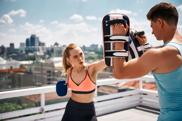 Entrenador masculino está teniendo entrenamiento de boxeo con la mujer en el techo — Foto de Stock