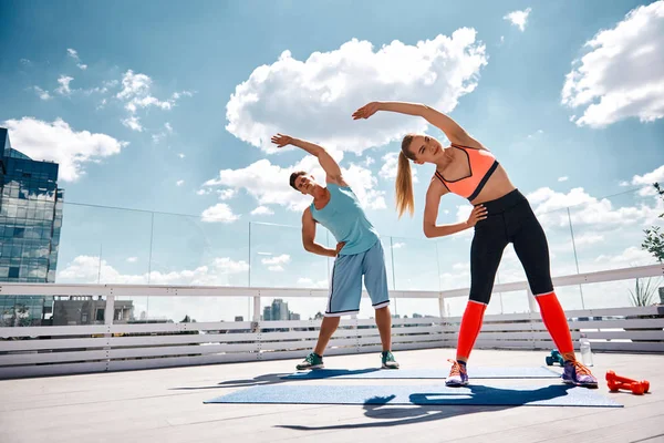 Desportivo masculino e feminino estão fazendo fitness no telhado — Fotografia de Stock