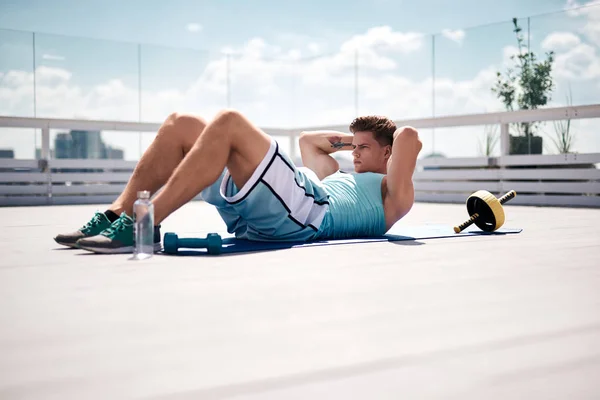 Shredded young man is training abdominal in city center