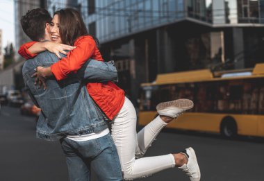 Tam uzunlukta yan görünüm mutlu kadın ve erkek birbirlerini sevinçle kucaklayan. O onu içerik ile sarılıyor iken genç erkek kız elinde tutuyor. Kopya alanı sağ tarafında
