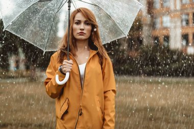 Dışarıda yağmur altında duran memnun kadın