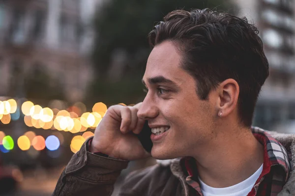 Mosolygó fiatal ember beszél telefonon szabadban — Stock Fotó