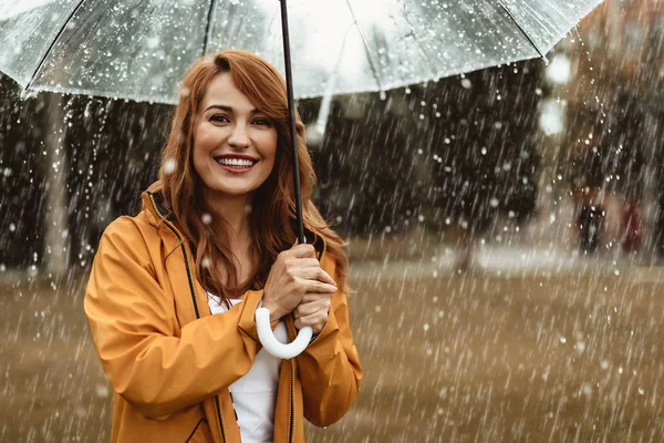 Счастливая девушка стоит на улице во время дождя — стоковое фото