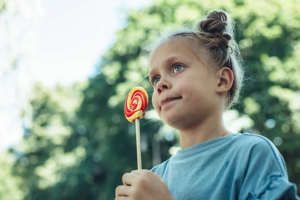 Criança feliz segurando doces no parque — Fotografia de Stock