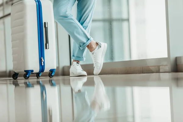 Pies masculinos en zapatillas de deporte cerca del equipaje — Foto de Stock