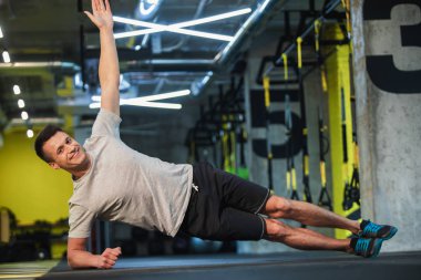 Gülümseyen adam yan tahta spor salonunda yapıyor