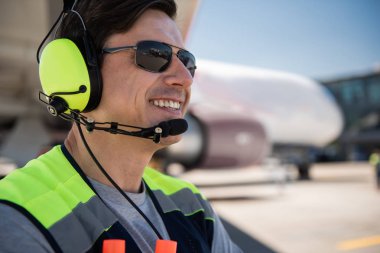 Güneş gözlüğü ve gülüyor kulaklık Havaalanı işçi