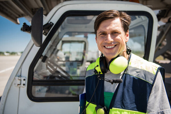 Smiling airport worker posing near vehicle