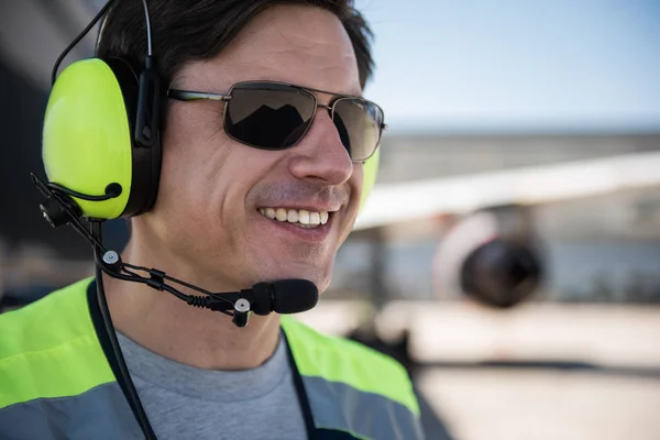 Cheerful airport worker in sunglasses and headset
