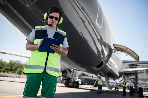 Працівник аеропорту заповнює документи під час перевірки членів екіпажу перед польотом — стокове фото