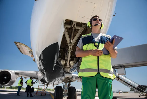 Працівник аеропорту з буфетом, що стоїть перед літаком під час роботи колег — стокове фото