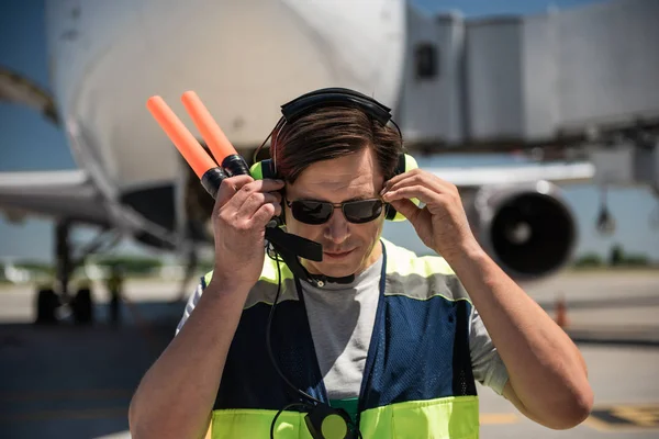 Marshaller de aviación tocando gafas de sol mientras sostiene varitas de señal — Foto de Stock