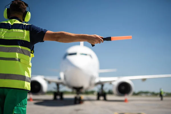 Авіаційний маршал у навушниках, спрямованих на пасажирський літак — стокове фото