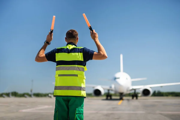 Pracownik lotniska, kierowanie samolotu w odpowiedniej pozycji — Zdjęcie stockowe