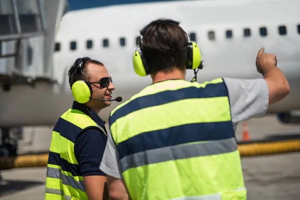 Flughafenmitarbeiter hört Kollege zu und lächelt — Stockfoto