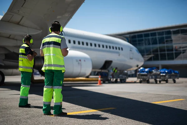 Pracovníci letiště při pohledu na moderní letadla — Stock fotografie