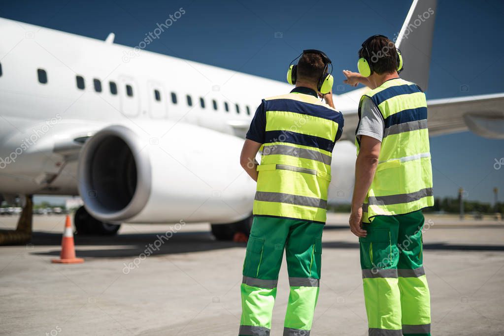Ground crew members looking at passenger plane