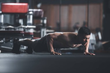 Motive üstsüz adam şınav kapalı yapıyor