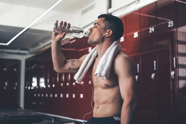 Calm man is relaxing in gym cloakroom