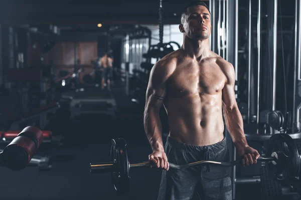 El hombre consciente está entrenando brazo con barra en el gimnasio —  Fotos de Stock