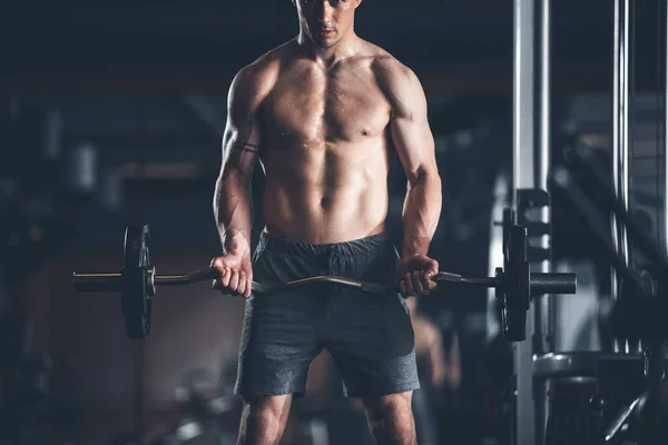 Gespannen man is het opheffen van zware apparatuur in de sportschool — Stockfoto
