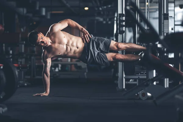 Determined sportsman is doing side plank in gym — Stock Photo, Image