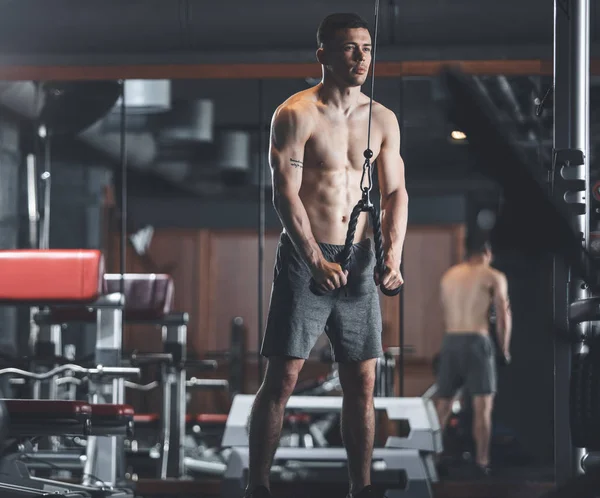 Zdecydowany sportowiec jest za pomocą kabli i koła pasowe w siłowni — Zdjęcie stockowe