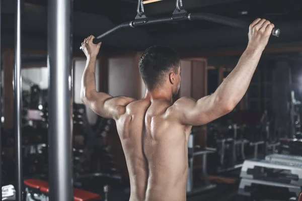 Man is exercising latissimus with equipment indoors — Stock Photo, Image