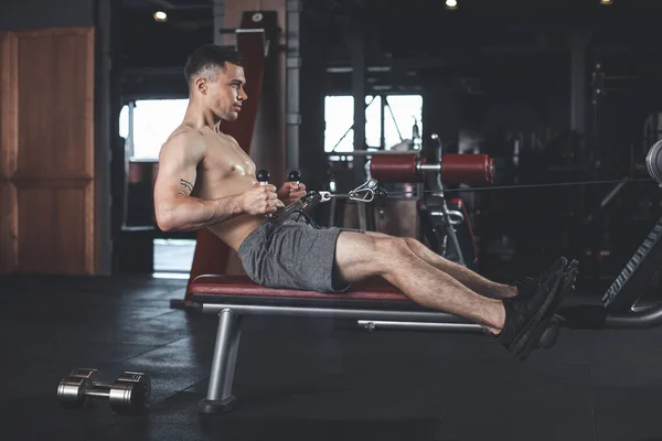 O desportista está alternando dumbbell e treino de máquina dentro de casa — Fotografia de Stock