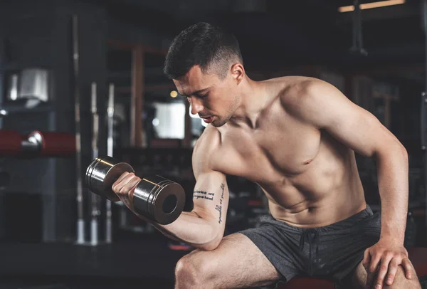 Strained man is training biceps in sport club — Stock Photo, Image