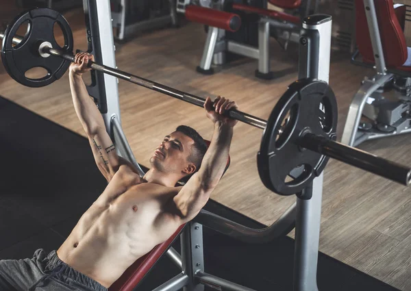 Ripped male is using heavy equipment in gym — Stock Photo, Image