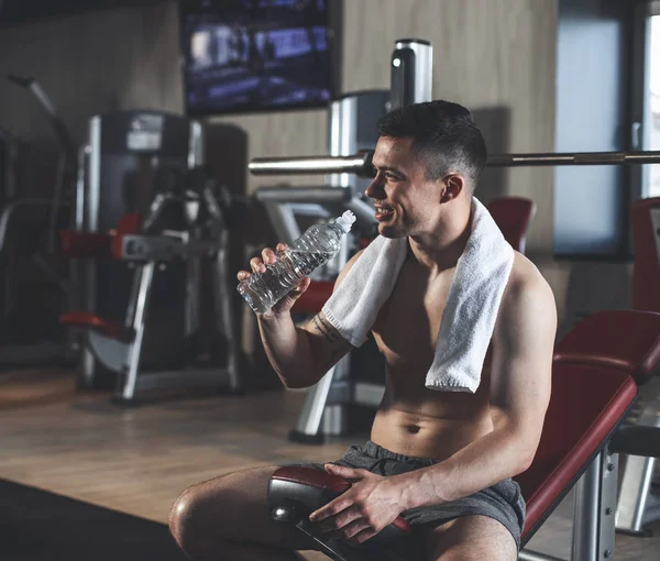 Позитивний культурист п'є воду під час внутрішніх тренувань — стокове фото