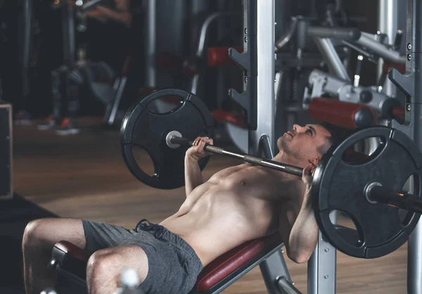 Concentrated man is lifting barbell in sport club — Stock Photo, Image