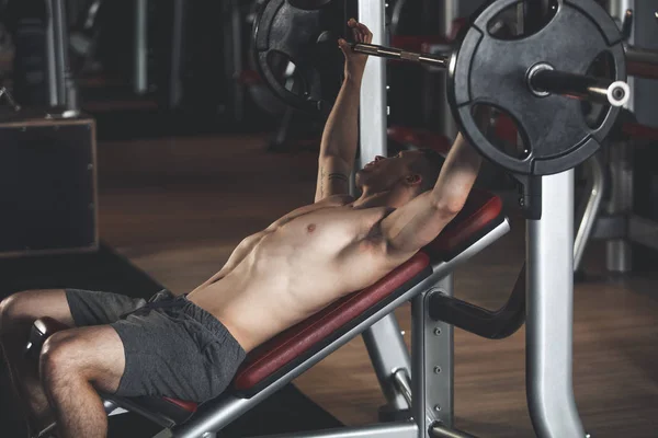 Atleta está se exercitando com máquina e peso no ginásio — Fotografia de Stock