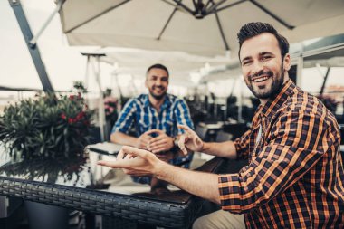 Arkadaşıyla masada oturan neşeli sakallı adam arka plan bulanık