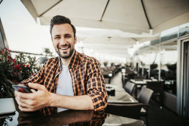 Masada oturan ve cep telefonu holding neşeli sakallı adam