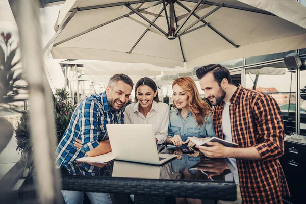 Grupp leende vänner i café tittar på laptop — Stockfoto