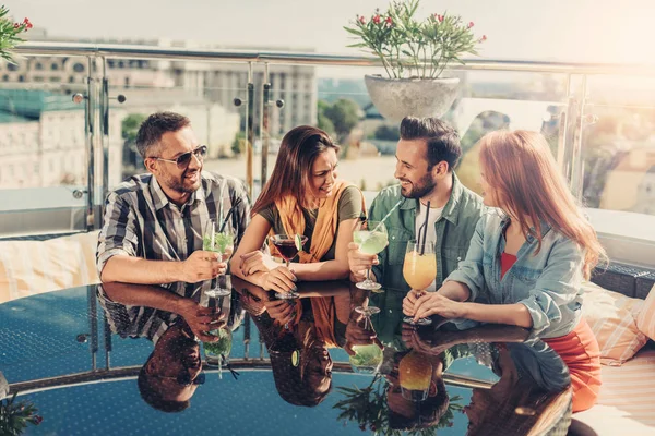 Dos parejas jóvenes en el bar al aire libre charlando y sosteniendo bebidas — Foto de Stock