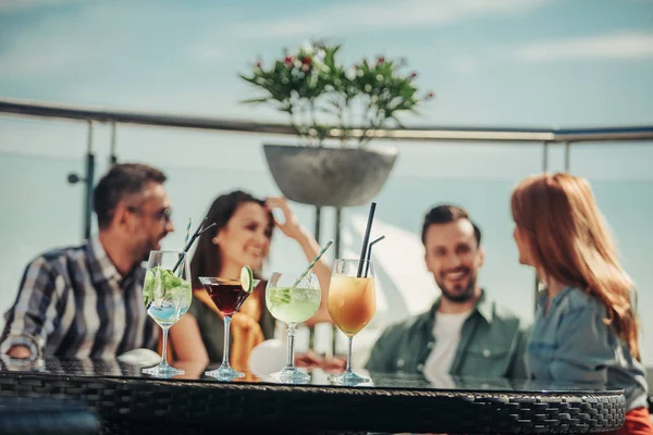 Různé nápoje alkohol na stole s veselou společností na rozostřeného pozadí — Stock fotografie