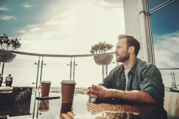 Hombre sereno sentado a la mesa con tazas de café —  Fotos de Stock