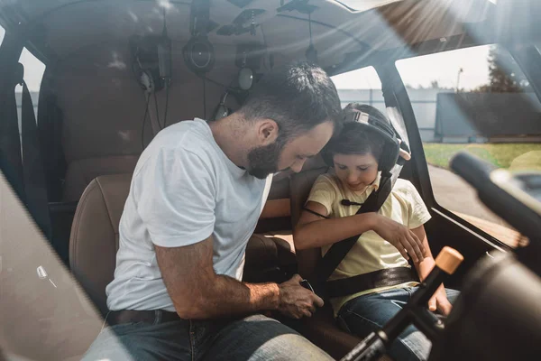 Tranquilo hombre instruyendo chico satisfecho en helicóptero — Foto de Stock
