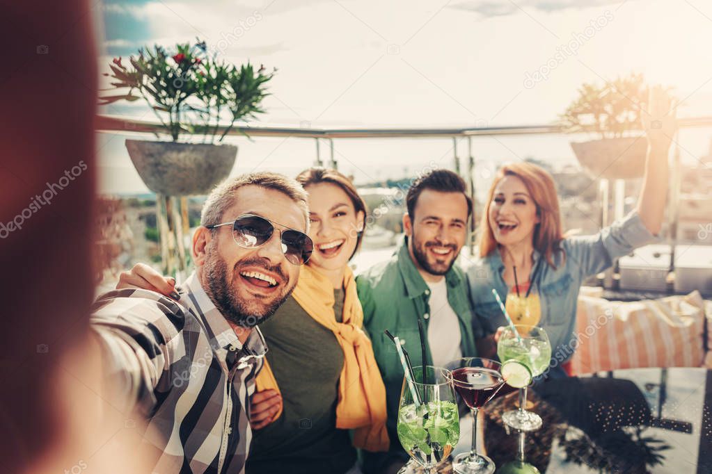 Cheerful friends making selfie at rooftop bar
