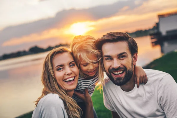 Fröhliche Eltern umarmen ausgehende kleine hübsche Mädchen — Stockfoto